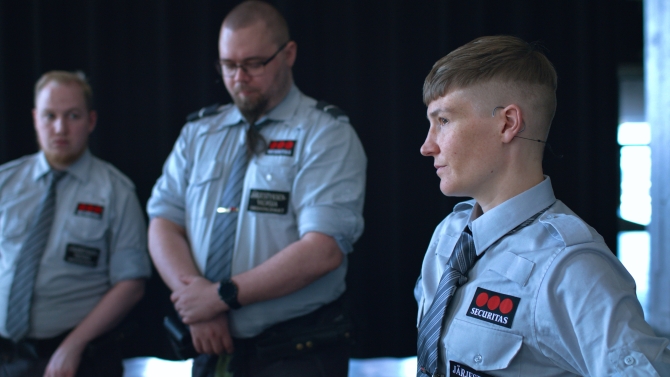 There are three people in a guard suit. The one in the front is artist Pilvi Takala.