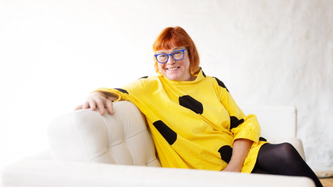 Kristiina Drews istuu sohvalla ja hymyilee.