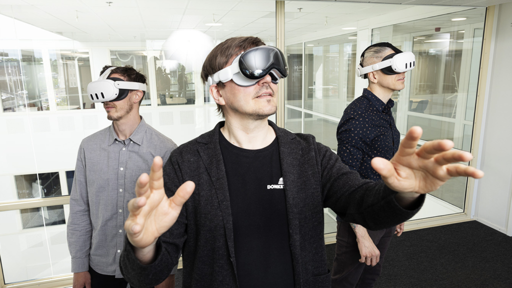 Kolme miestä VR-lasit päässä. 